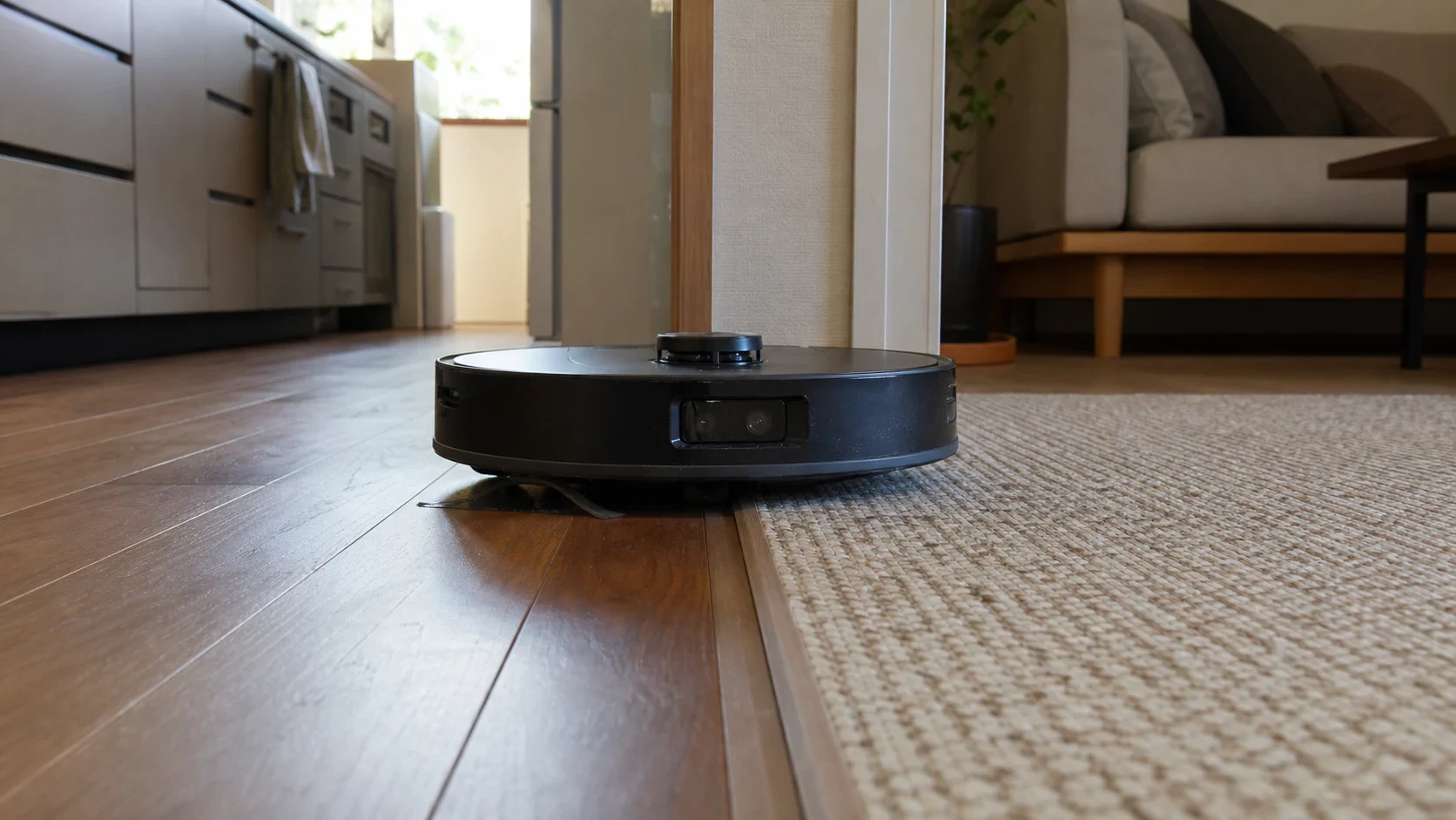 キッチンの硬い床と短い毛足のラグの境界を進むロボット掃除機