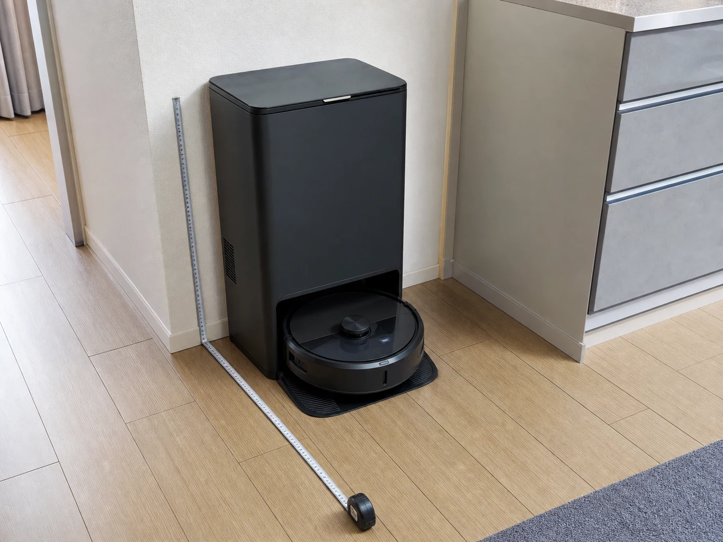 壁際のステーションとロボット掃除機の周囲をメジャーで測る様子