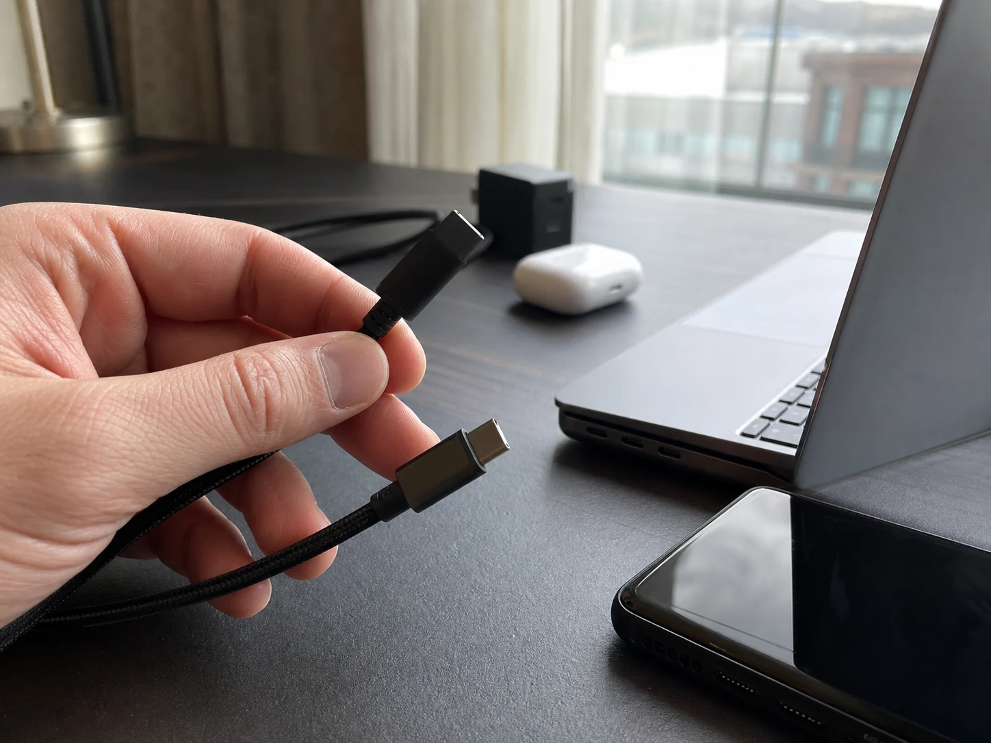 USB-CケーブルとUSB-Aケーブルの端子を出張用の机で見比べる場面